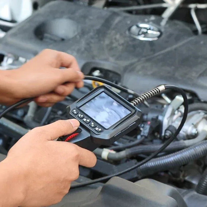 Hands using a handheld borescope inspection camera to examine a car engine